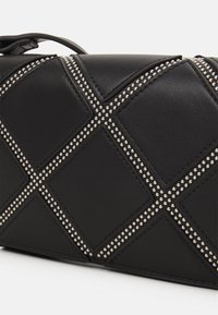 Sort læder clutch taske med diamantmønstret quiltning, dekoreret med sølvnitter langs sømmene. Har en lynlåslukning og justerbar rem.