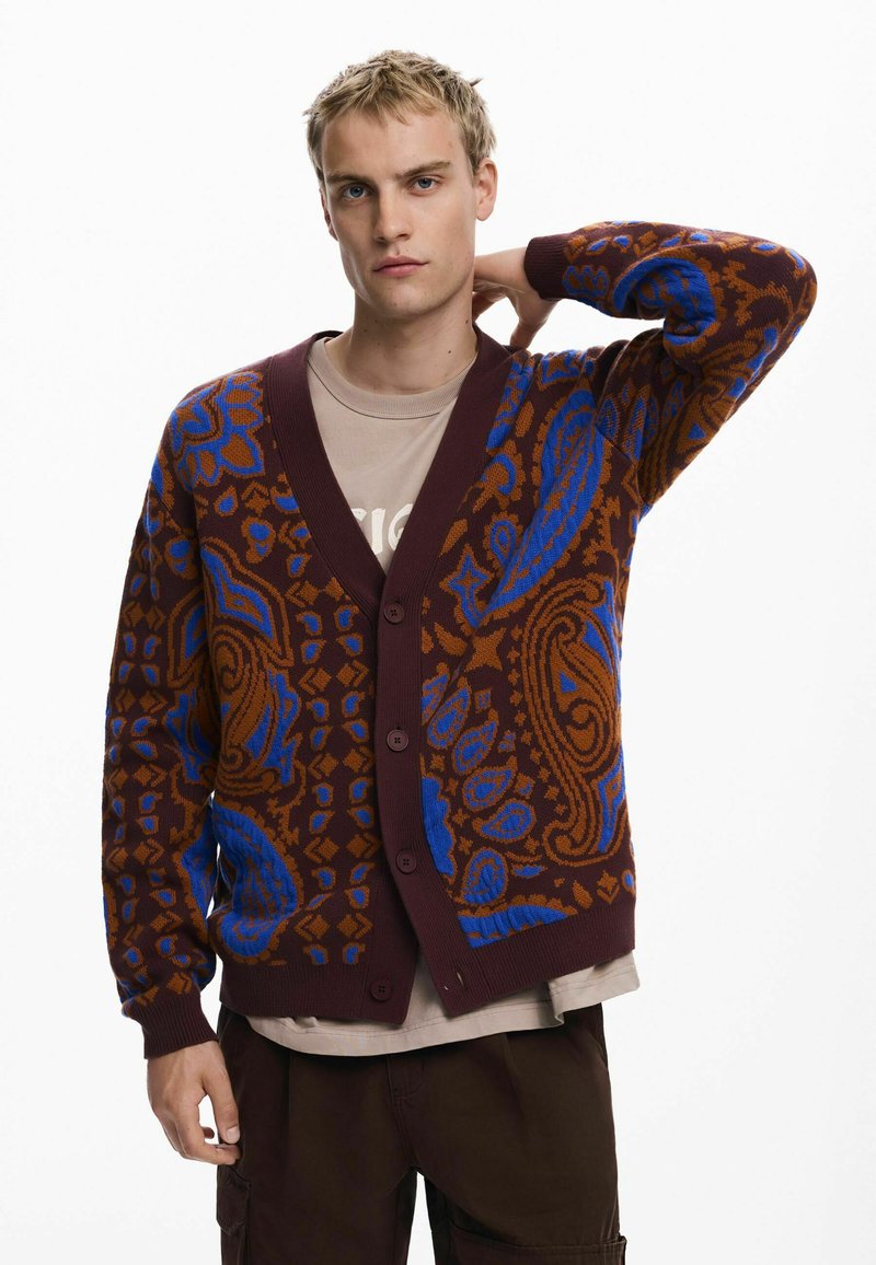 Cárdigan de punto con un patrón de paisley en marrón, azul y naranja, con un escote en V profundo y cinco botones en la parte delantera.
