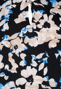 Blomstret top med en mørk baggrund, der har beige og blå blomstermønstre. Hjerteformet halsudskæring med en dekorativ sølvknap.