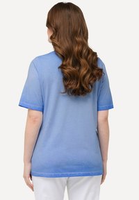 Camiseta azul de manga corta, con una tela ligeramente texturizada, un corte relajado y un ribete azul contrastante en las mangas y el dobladillo.