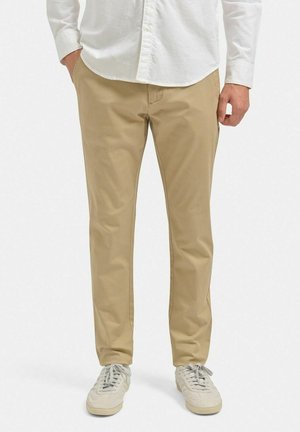 Beige bomulds chinos med lige pasform, der har sidelommer og en glat tekstur, parret med lyse sneakers.