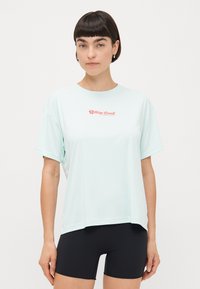 Ljus mintgrön t-shirt med korta ärmar, tillverkad av ett ventilerande material. Har en röd logotyp på bröstet och en avslappnad, oversized passform.
