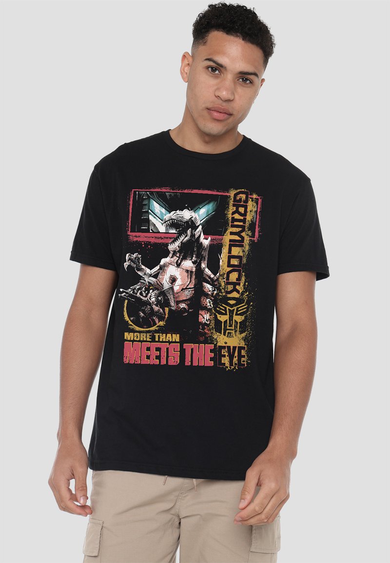 Schwarzes T-Shirt mit einem Grafikdruck eines robotischen Dinosauriers und dem Text "Grimlock" in Gelb und Pink. Kurze Ärmel und lockere Passform.