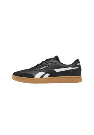 Zapatilla Reebok de corte bajo en blanco y negro con suela de goma y logo de Reebok en el lateral y el talón, vista desde el lado exterior.