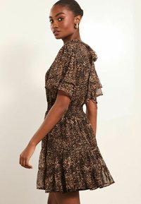 Rochie cu imprimeu leopard maro, cu mâneci scurte și evazate, tiv ondulat și talie strânsă, realizată dintr-un material ușor și fluid.
