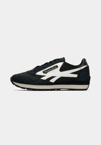 Scarpa sportiva nera e grigia in materiale scamosciato e sintetico. Presenta accenti bianchi del logo e una suola in gomma testurizzata. Design classico.
