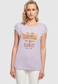 Lilac short-sleeve t-shirt featuring a graphic with a yellow-orange dragonfly and text. Soft fabric with a relaxed fit.