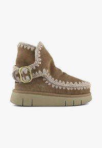 Bottine en daim marron avec coutures contrastées beige, bout rond et détail boucle sur le côté. Semelle en caoutchouc avec motif texturé pour une meilleure adhérence.