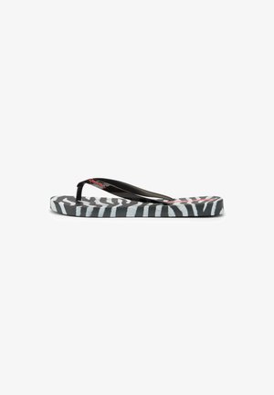 Flip-Flop mit schwarz-weißer Zebra-Sohle und schwarzem Zehensteg mit rotem Markenlogo auf weißem Hintergrund.