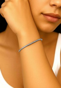 Blå metall armbånd på et lys brun håndledd, glatt tekstur, sylindrisk form, båret rett over håndleddsbeinet.