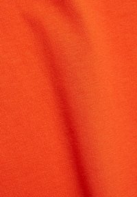 Klarr orange tyg med en jämn, texturerad yta som har ett ribbat mönster. Materialet verkar lätt och flexibelt.