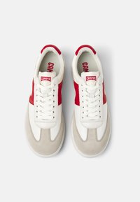 White leather sneakers with red accents, lace-up design, beige suede toe cap, and "CAMPER" branding on the tongue and insole.