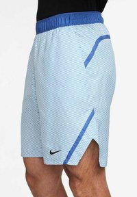 Shorts de sport bleu clair avec un motif en losange, logo Nike noir et accents bleus. Dispose d'une taille élastique et d'éventails sur les côtés.