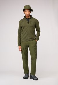 Olivgrön fleecejacka med dragkedjsfickor, i kombination med olivgröna cargobyxor. En matchande mjuk hatt fulländar outfiten. Texturerad och funktionell design.