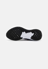 Sole delle sneakers Nike in gomma nera con motivi di presa circolari, la suola intermedia presenta una sezione bianca con il logo Nike. Design piatto, superficie testurizzata.