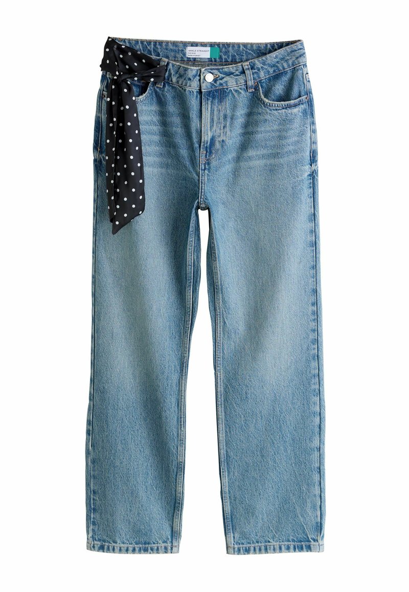 Svetlomodré džínsové nohavice s priamym strihom, zdobené čiernou šatkou s bodkami, priviazanou na páse. Viditeľná je opotrebovaná textúra.