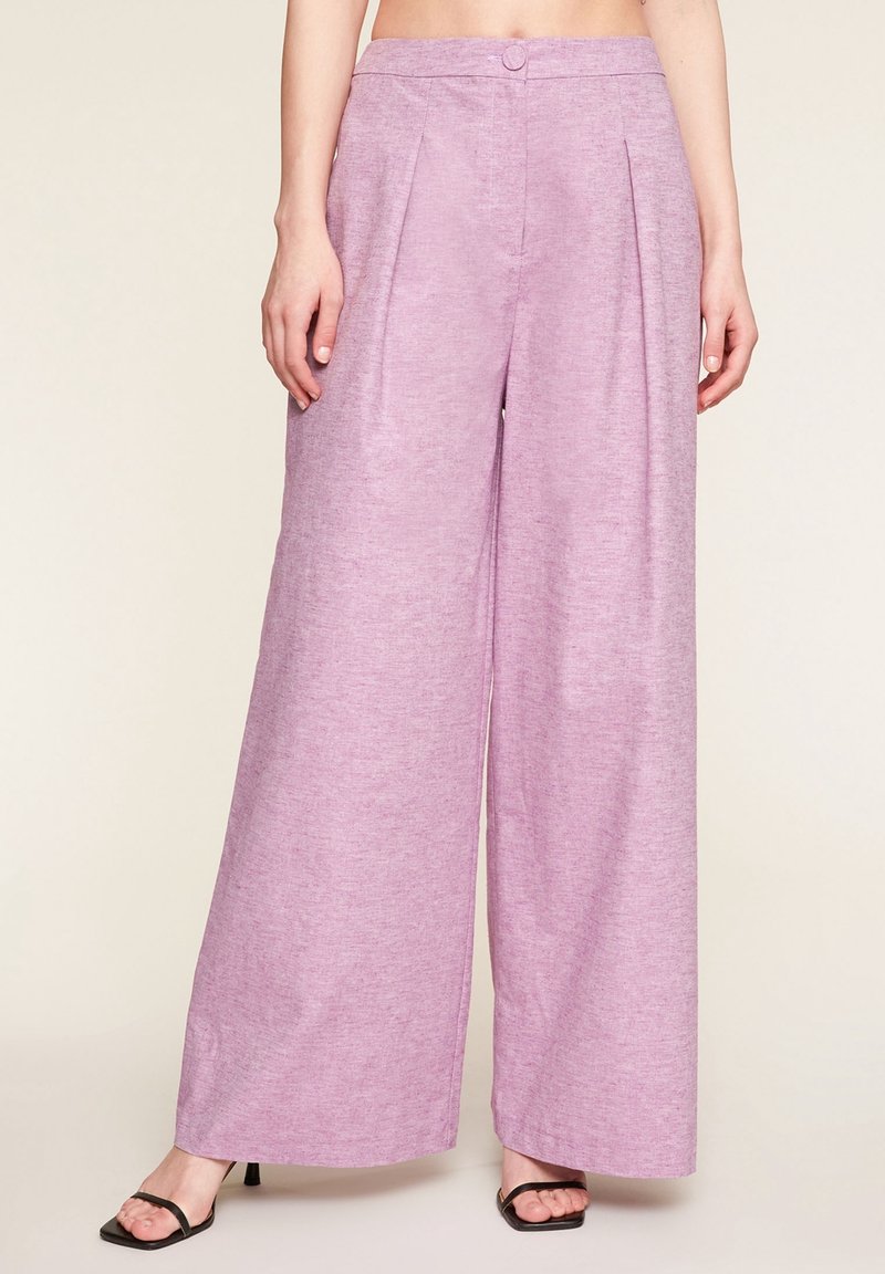 Lavender wide-leg trousers made of textured fabric, featuring a front button closure and pleats, paired with black strappy heels.