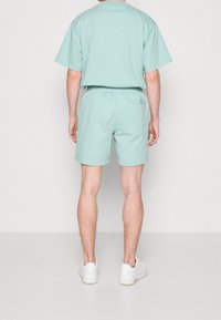 Vihreä minttuvärinen puuvillapaita ja shortsit, rento malli, lyhyet hihat, elastinen vyötärö, shortsit sisältävät takataskun, yhdistetty valkoisiin lenkkikenkiin.