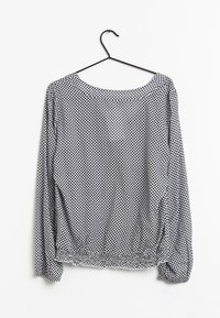 Blusa a maniche lunghe con scollo rotondo, realizzata in tessuto leggero. Presenta un motivo a diamante bianco e nero e un orlo elasticizzato.