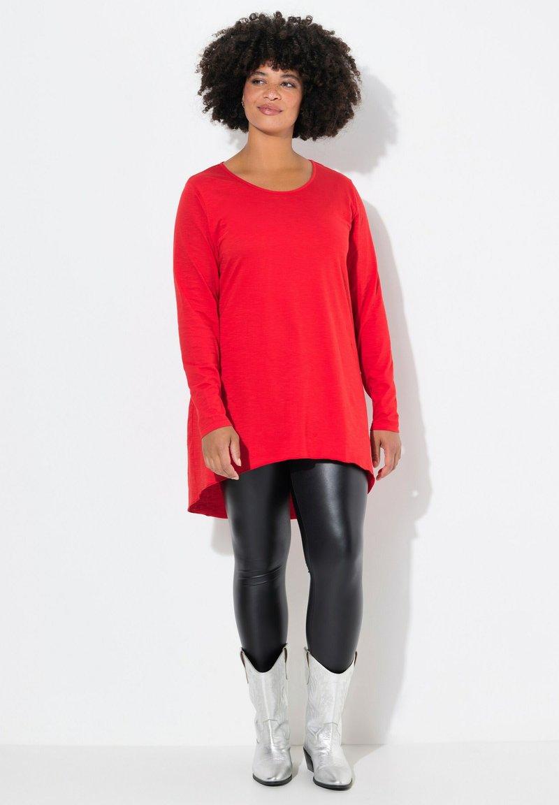 Rote Tunika mit langen Ärmeln und abgerundetem Saum, kombiniert mit schwarzen Leggings und silbernen Cowboystiefeln, im lässigen Schnitt und mit weichem Stoff.