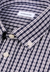Chemise à carreaux bleu marine et blanc avec boutons au col et étiquette de marque "seidensticker" visible à l'intérieur du col.