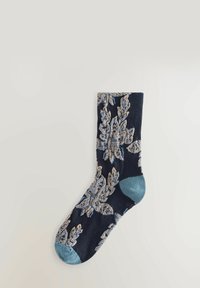 Calcetín navy con patrón floral en beige y azul. Punta y talón reforzados en azul claro. Textura suave, longitud hasta la mitad de la pantorrilla.