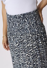 Jupe maxi avec une taille élastique froncée, arborant un motif bleu marine, blanc et bleu clair dans un tissu fluide et texturé.