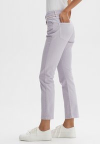 I jeans di cotone lilla presentano una vestibilità slim, design a cinque tasche e una lunghezza cropped, abbinati a sneakers bianche per un look casual.