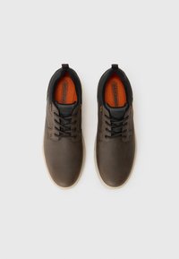 Chaussures en cuir marron avec des accents en textile noir, présentant un bout rond, un laçage à l'avant et des semelles intérieures orange ; surfaces texturées pour une meilleure adhérence.