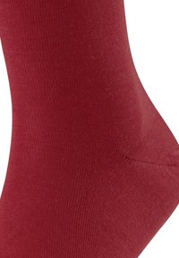 Punainen puuvillasukka, jossa on sileä pinta, resorikuvio ja saumaton varvas. Sukka on nilkkapituisen mallinen ja istuu tiukasti jalassa.