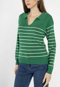Pull vert à rayures horizontales blanches, avec un col en V et un collier. Fabriqué en matériau doux avec des manches ajustées et un ourlet côtelé.