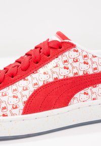 Punane tossud tekstureeritud nubukist ülaga, millel on valgest kangast külg, kaunistatud Hello Kitty mustritega ja valge täpikatega tald.
