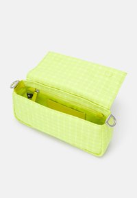 Borsa rettangolare giallo neon con un motivo a pois testurizzato, dotata di chiusura a scatto magnetico e tasca interna con zip. Accompagnata da dettagli in metallo argentato.
