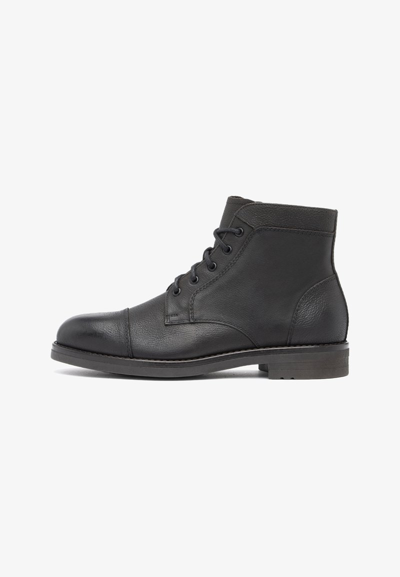 Bottine noire en cuir à lacets avec bout rond, détails cousus et petit talon empilé sur fond blanc.