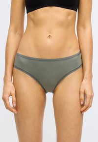 Culotte hipster en coton vert olive avec un bord en dentelle festonnée et une texture lisse. Coupe taille mi-haute avec une forme ajustée.