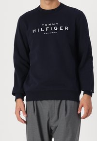 Sweatshirt bleu marine en coton, avec un col rond et des manches longues. Logo imprimé "TOMMY HILFIGER EST.1985" sur le devant.