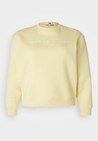 Sweatshirt jaune en tissu doux, avec un col rond, des poignets côtelés et le logo "TOMMY HILFIGER EST. 1985" en blanc.