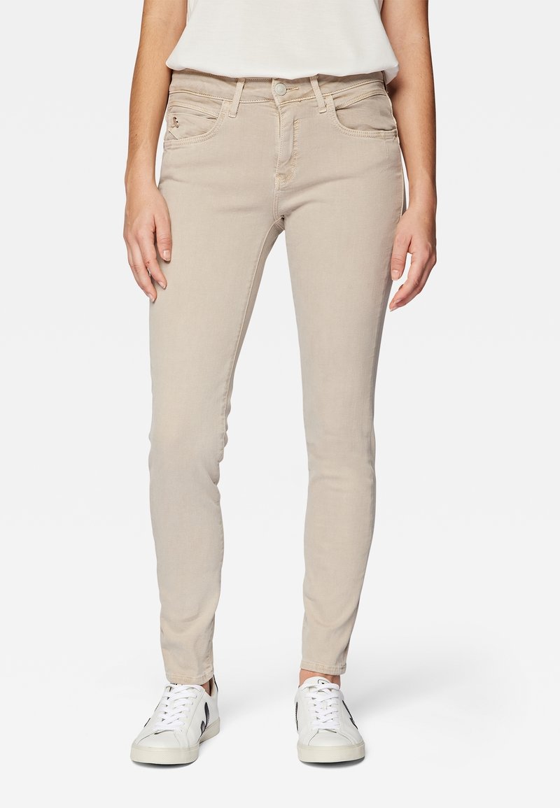 Beige skinny jeans made of denim with a smooth texture, featuring five pockets, a front button closure, and contrasting stitching details.