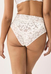 Witte kant hoge taille slipjes met bloemmotieven, geschulpte randen en een doorschijnende textuur, aangevuld met een solide binnenlaag.