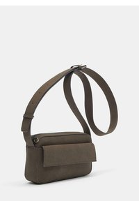 Borsa a tracolla verde oliva realizzata in tessuto morbido e testurizzato. Presenta una patta ripiegabile, chiusura con zip e una tracolla regolabile. Forma rettangolare.