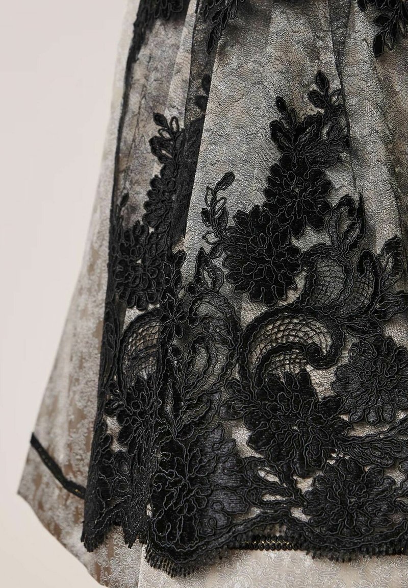 Schwarze Spitze ziert einen durchsichtigen grauen Stoff, der komplexe florale Muster und subtile Texturen aufweist, mit einem zarten, geschwungenen Saum.