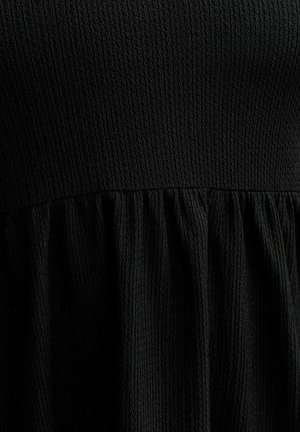 Vestido negro con tejido texturizado; presenta un top ajustado y una falda acampanada y fruncida a la altura de la cintura. Diseño simple y monocromático.