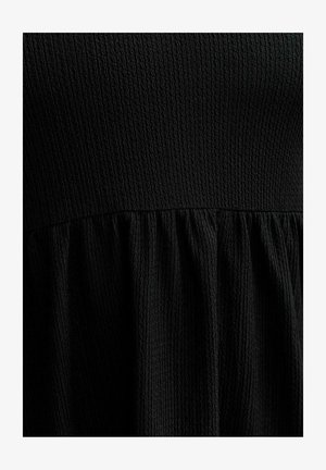 Robe noire en tissu texturé ; présente un haut ajusté et une jupe évasée plissée à la taille. Design simple et monochrome.