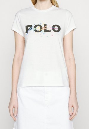 Camiseta blanca de algodón con un atrevido logo negro "POLO" y acentos de salpicaduras coloridas. Cuello redondo y mangas cortas.