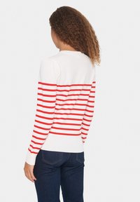 Maglione a righe con base bianca e righe rosse orizzontali. Polsini e orlo a costine; design aderente con maniche lunghe e scollo rotondo.
