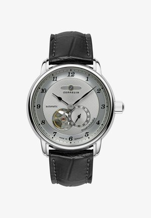 Automatische Uhr mit einem silbernen strukturierten Zifferblatt, schwarzem Lederarmband, Edelstahlgehäuse und sichtbarem Uhrwerk auf 6 Uhr.