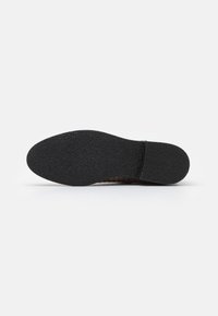 Semelle en caoutchouc noir avec surface texturée, présentant une forme courbée et un motif subtil, conçue pour la traction et la durabilité.