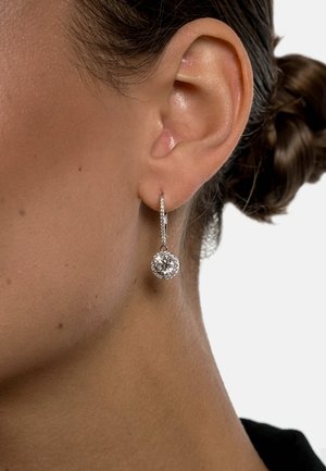 Silver hoop earrings with a circular, sparkling gemstone pendant, set in a bezel with small accent stones around the edge.