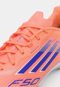 Scarpa da calcio indoor neon arancione con strisce blu, tomaia in rete, design testurizzato e marchio prominente che recita "F50" e "INDOOR LEAGUE."