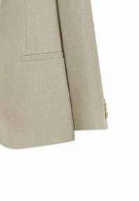 Manche de blazer beige clair et partie avant inférieure avec poche à rabat et quatre boutons beiges sur le poignet, tissu texturé.